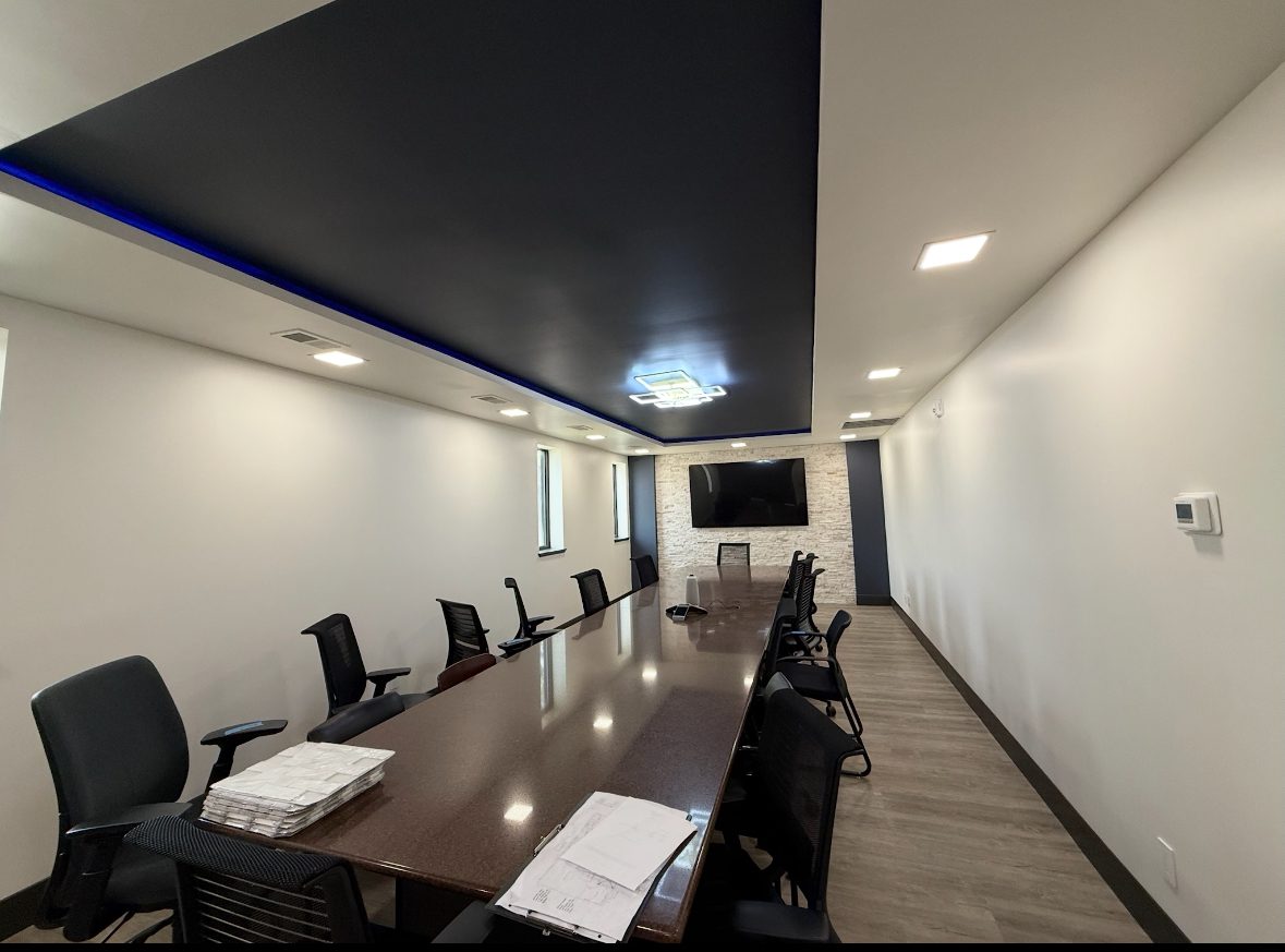 Modern conference room with a long table and black office chairs.